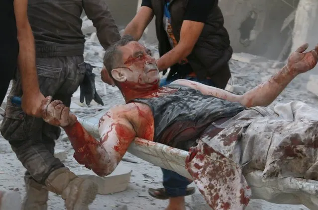 A wounded man is being carried as search and rescue team members evacuate casualties from the rubbles after the Syrian regime forces airstrikes hit Aleppo's opposition controlled Al-Ansari town, Syria on September 22, 2016. (Photo by Ibrahim Ebu Leys/Anadolu Agency/Getty Images)