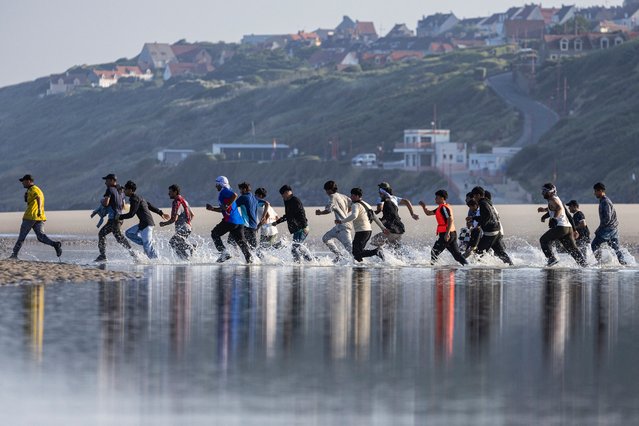 Migrants rush to try to board a smuggler's boat in an attempt to cross the English Channel on the beach of Equihen, northern France, on June 30, 2025. (Photo by Sameer Al-Doumy/AFP Photo)