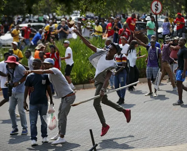 Students throw stones during a confrontation with security guards as they protest over planned increases in tuition fees outside the (UJ) University of Johannesburg October 22, 2015. (Photo by Siphiwe Sibeko/Reuters)