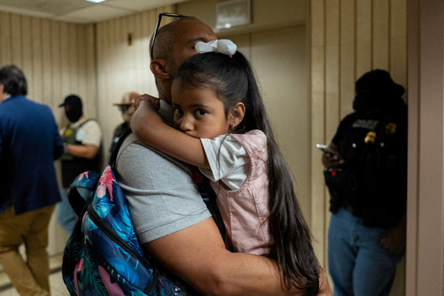 A father carrying his daughter on his way to an immigration hearing walks past federal immigration officers at the U.S. immigration court in Manhattan, in New York City on July 11, 2025. (Photo by David 'Dee' Delgado/Reuters)