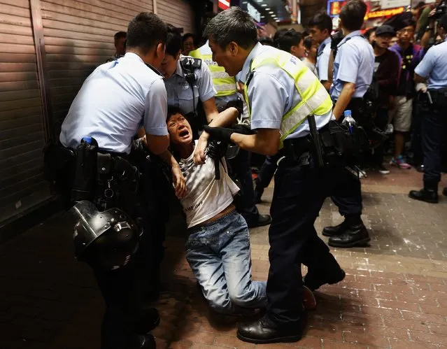 A passerby frightened by police action is helped on a pavement at Mongkok shopping district in Hong Kong November 26, 2014. Hong Kong police on Wednesday cleared one of the largest protest sites that has choked the city for months, arresting scores of pro-democracy activists in what could be a turning point in the fight to wrest greater political freedom from Beijing's control. (Photo by Bobby Yip/Reuters)