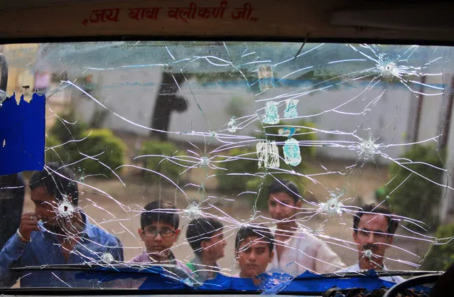 Indian civilians look at a school bus riddled with bullet marks, allegedly from firing from the Pakistan side of the border, at a residential area near the international border at Mawa village, in Samba district, about 58 kilometers south of Jammu, India, Saturday, October 24, 2015. India on Friday accused Pakistan of a cease-fire violation in Kashmir in which one Indian civilian was killed and another was wounded. (Photo by Channi Anand/AP Photo)