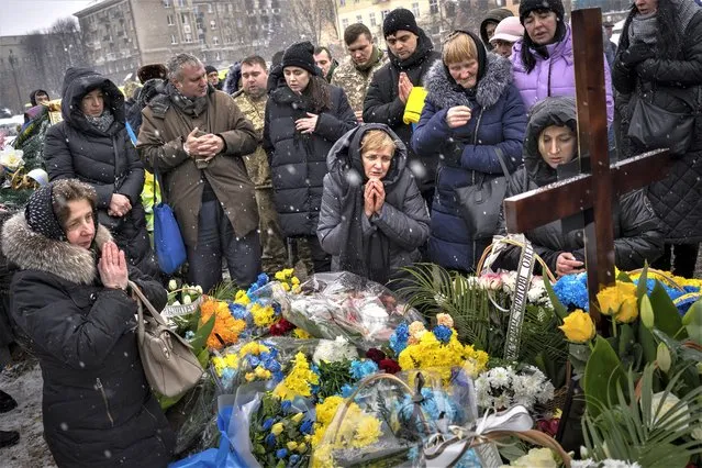 Nadia, center, prays at the grave of her son Oleg Kunynets, a Ukrainian military servicemen who were killed in the east of the country, during his funeral in Lviv, Ukraine, Tuesday, February 7, 2023. (Photo by Emilio Morenatti/AP Photo)