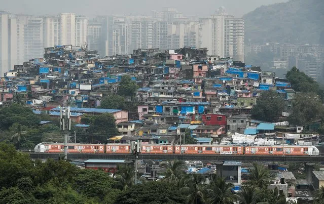 A metro train moves past slums and buildings after the restart of its operations, amidst the spread of the coronavirus disease (COVID-19), in Mumbai, India October 19, 2020. (Photo by Francis Mascarenhas/Reuters)