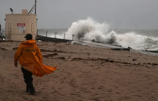 A police officer walks along the beach as waves crash ashore as Hurricane Matthew approaches the area on October 6, 2016 in Singer Island, Florida. The hurricane is expected to make landfall sometime this evening or early in the morning as a possible Category 4 storm. (Photo by Joe Raedle/Getty Images)