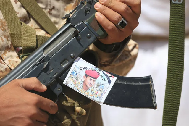 A soldier holds a rifle with a photo of Major-General Abdel-Rab al-Shadadi, a top general in forces loyal to Yemeni President Abd-Rabbu Mansour Hadi's government killed in fighting with Iran-aligned Houthi troops, during his funeral in Marib city, Yemen October 9, 2016. (Photo by Ali Owidha/Reuters)