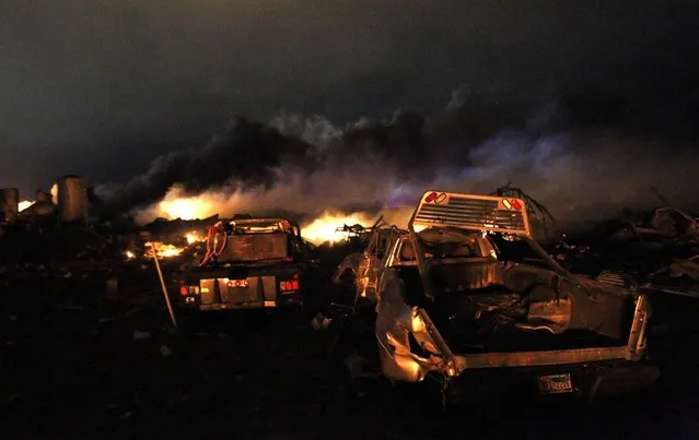 Vehicles are seen near the remains of a fertilizer plant burning after an explosion at the plant in the town of West, near Waco, Texas early April 18, 2013. The deadly explosion ripped through the fertilizer plant late on Wednesday, injuring more than 100 people, leveling dozens of homes and damaging other buildings including a school and nursing home, authorities said. (Photo by Mike Stone/Reuters)