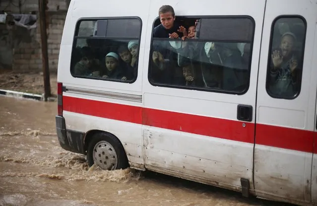 Palestinian students look out from a bus as they drive pass a street flooded by rain water in Khan Younis in the southern Gaza Strip, November 9, 2015. (Photo by Ibraheem Abu Mustafa/Reuters)