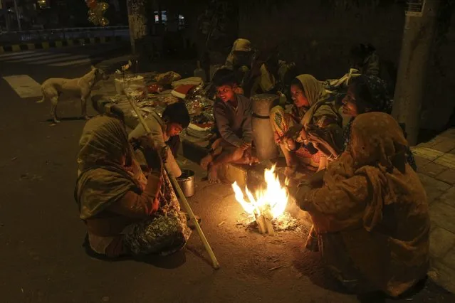 An Indian family living on a roadside keeps themselves warm by sitting around a bonfire in Ahmedabad, India, Friday, December 26, 2014. Cold wave conditions continues unabated in the northern region with fog enveloping most areas and affecting transport services. (Photo by Ajit Solanki/AP Photo)