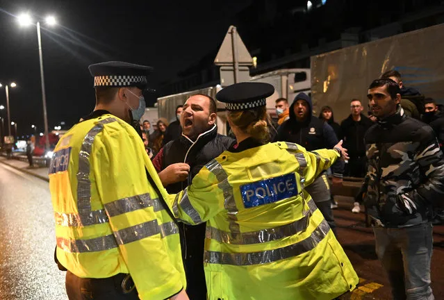 Drivers and passengers of vehicles trying to access the port in Dover, south east England on December 22, 2020, argue with police officers after France closed its borders to accompanied freight arriving from the UK due to the rapid spread of a new coronavirus strain. The British government said Tuesday it was considering tests for truckers as part of talks with French authorities to allow the resumption of freight traffic suspended due to a new coronavirus strain. Britain was plunged into fresh crisis last week with the emergence of a fresh strain of the virus, which is believed to be up to 70 percent more transmissible than other forms. (Photo by Justin Tallis/AFP Photo)