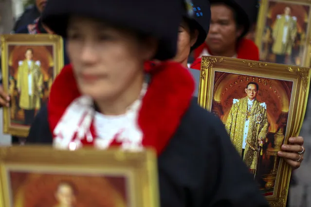 Mourners hold up pictures of Thailand's late King Bhumibol Adulayadej as they wait in line to enter the Throne Hall at the Grand Palace for the first time to pay respects to his body that is kept in a golden urn in Bangkok, Thailand, October 29, 2016. (Photo by Athit Perawongmetha/Reuters)
