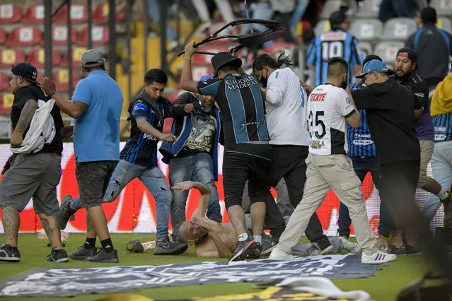Fans clash during a Mexican soccer league match between the host Queretaro and Atlas from Guadalajara, at the Corregidora stadium, in Queretaro, Mexico, Saturday, March 5, 2022. Multiple people were injured during the brawl, including two critically. (Photo by Sergio Gonzalez/AP Photo)