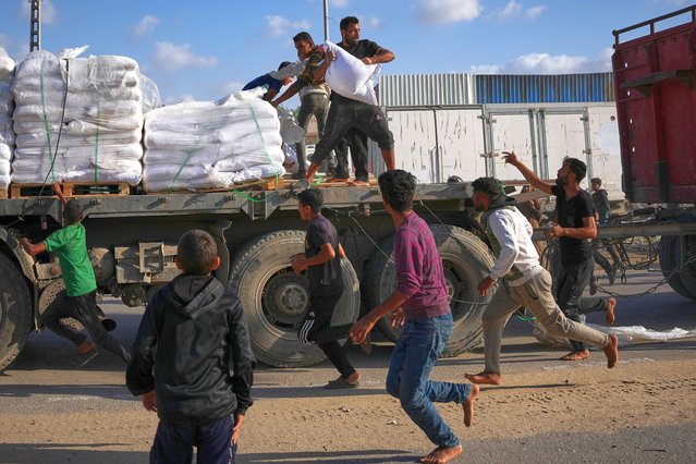 Palestinians grab sacks of flour from a moving truck carrying World Food Programme (WFP) aid as it drives through Deir al-Balah in central Gaza, Saturday, November 15, 2025. (Photo by Abdel Kareem Hana/AP Photo)