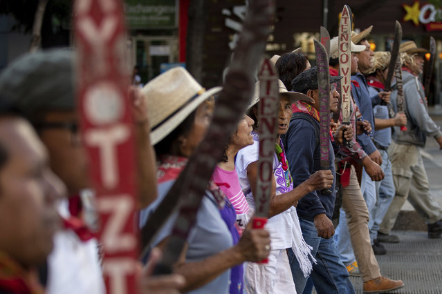 A group of men march holding machetes upright during a protest to raise awareness of 43 students who went missing nearly four years ago, in Mexico City, Saturday, May 26, 2018. The rural college students mysteriously vanished on Sept. 26, 2014 in Iguala when they were interrupted on their way to demonstration by police. Family members and protestors continually march to demand justice for the 43. (Photo by Anthony Vazquez/AP Photo)
