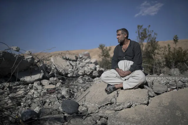 Yusuf Mohammed Yusuf sits on the debris of his brother's house, that was destroyed by an airstrike, in Faziliya, north of Mosul, Iraq, Wednesday, November 2, 2016. Yusuf said that an airstrike hit the house of his brother and killed eight members of his family in the village of Faziliya, which was recently retaken by Iraqi Kurdish forces from the Islamic State group. (Photo by Felipe Dana/AP Photo)