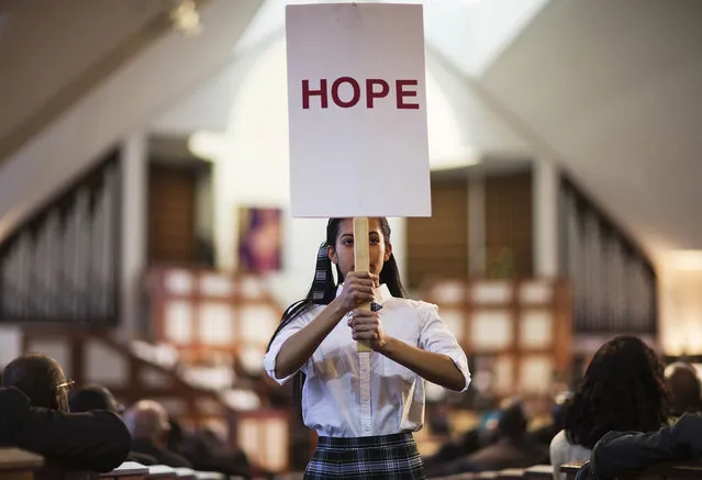 Jaiya Smith carries a sign down the aisle during a service honoring Rev. Martin Luther King Jr. at Ebenezer Baptist Church, where King preached, Monday, January 19, 2015, in Atlanta. (Photo by David Goldman/AP Photo)