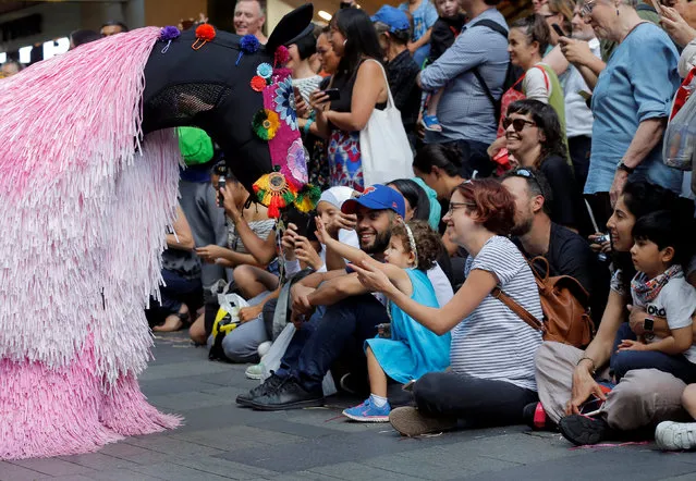 A girl reaches out to touch a dancer dressed as a horse by U.S. artist Nick Cave during his first major work shown in Australia entitled HEARD.SYD in Sydney, Australia November 10, 2016. Over several days the live art performance will feature 30 'horses' dancing to live percussion beats in suits made from coloured raffia plant fibres. (Photo by Jason Reed/Reuters)