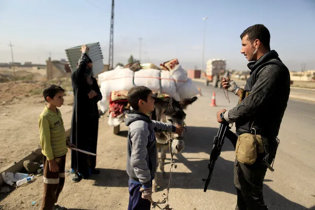 A boy who is fleeing the fighting between Islamic State and the Iraqi army in Mosul with his family talks to a special forces soldier at the checkpoint in Kokjali, east of Mosul, Iraq November 12, 2016. (Photo by Zohra Bensemra/Reuters)
