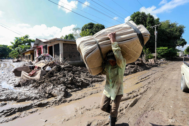 A local resident, victim of tropical storms Eta and Iota, carries a matress along a street covered in mud during a visit of Queen Letizia of Spain (not depicted) in the community of Flores de Oriente, La Lima municipality, Cortes department, in northern Honduras on December 15, 2020. Queen Letizia is in the country on an official two-day visit to learn about the effects left by tropical storms Eta and Iota and deliver the first part of a 120-ton donation for the affected to cope with the situation. (Photo by Wendell Escoto/AFP Photo)