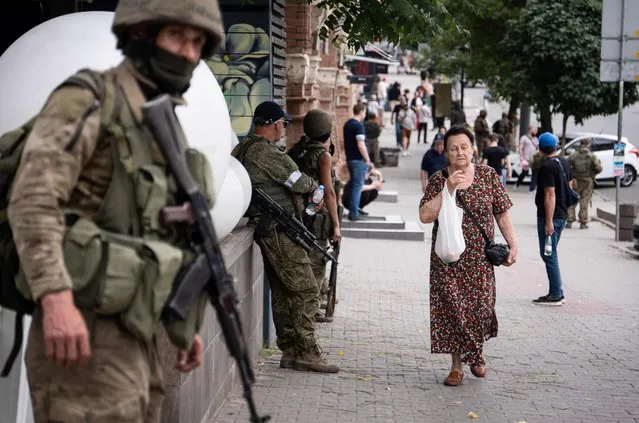 A local resident walks past members of Wagner group in Rostov-on-Don, on June 24, 2023. President Vladimir Putin on June 24, 2023 said an armed mutiny by Wagner mercenaries was a “stab in the back” and that the group's chief Yevgeny Prigozhin had betrayed Russia, as he vowed to punish the dissidents. Prigozhin said his fighters control key military sites in the southern city of Rostov-on-Don. (Photo by Denis Romanov/AFP Photo)