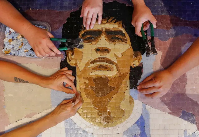 Gabriela Pereyra, Paula Soto, ad Gonzalo Lopez Lluch, members of the cultural orgaization Comado Maradona, prepare a mosaic as a homage to late Argentine soccer superstar Diego Armado Maradona, at their workshop, in Buenos Aires, Argentina on February 24, 2021. (Photo by Agustin Marcaria/Reuters)
