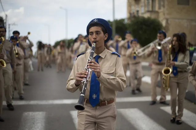 An Arab boy scout plays music during a procession parade to St. George church during a feast to commemorate the bringing of the remains of the great martyr St. George to Lod, Israel, Wednesday, November 16, 2016. Jerusalem's Greek Patriarch believes the church contains the tomb of St. George. (Photo by Ariel Schalit/AP Photo)