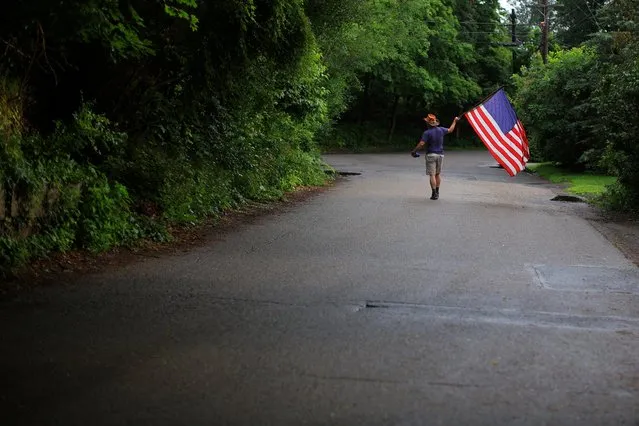 A man carrying a U.S. flag leads a local Fourth of July Parade in the Lanesville neighborhood of Gloucester, Massachusetts, U.S., July 4, 2023. (Photo by Brian Snyder/Reuters)
