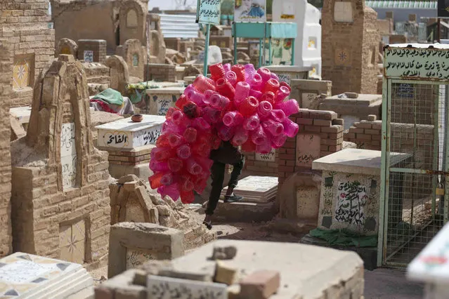 A mean sells plastic bottles at Wadi al-Salaam, or Valley of Peace, Shiite cemetery on the first day of Eid al-Fitr holiday that marks the end of the Islamic holy month of Ramadan, in Najaf, Iraq, Saturday, April 22, 2023. Wadi al-Salam is the world's biggest cemetery. (Photo by Anmar Khalil/AP Photo)