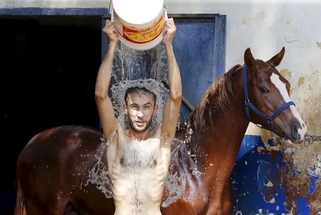 A man pours water over himself while washing a horse in order to cool it down as part of measures taken to ease the effect of a heatwave at the Beirut Hippodrome, Lebanon August 4, 2015. (Photo by Mohamed Azakir/Reuters)