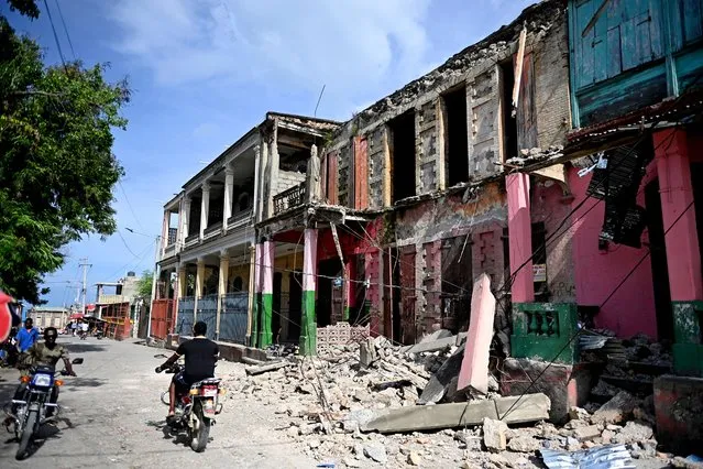 People drive past damaged buildings in Jeremie, Haiti, after an earthquake hit western Haiti on June 6, 2023. An earthquake shook parts of western Haiti on Tuesday, killing at least four people and injuring more than two dozen others, civil protection authorities said. The magnitude 4.9 quake occurred in the isolated Grand'Anse department nearly 300kms (185 miles) west of Port-au-Prince, at a relatively shallow depth of 10kms, according to the US Geological Survey. (Photo by Richard Pierrin/AFP Photo)