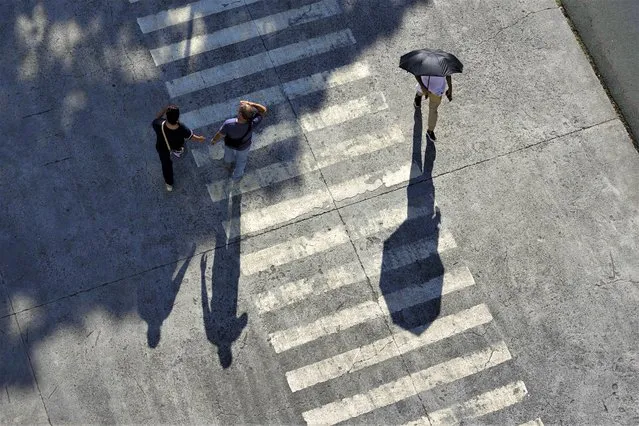 A man uses an umbrella to shield him from the afternoon sun in Manila, Philippines on Thursday, July 6, 2023. (Photo by Aaron Favila/AP Photo)