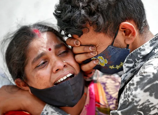A woman mourns with her son after her husband died due to the coronavirus disease (COVID-19) outside a mortuary of a COVID-19 hospital in Ahmedabad, India, April 20, 2021. (Photo by Amit Dave/Reuters)