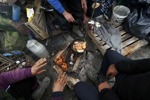 Migrants prepare their food outside shelters in a muddy field called the Grande-Synthe jungle, near Dunkirk, northern France, January 12, 2016. (Photo by Benoit Tessier/Reuters)