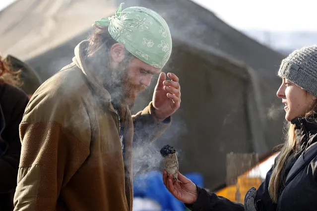 Healer Angie Spencer uses sage to perform an “energy smudging” ceremony with a veteran inside the Oceti Sakowin camp as “water protectors” continue to demonstrate against plans to pass the Dakota Access pipeline near the Standing Rock Indian Reservation, near Cannon Ball, North Dakota, U.S., December 3, 2016. (Photo by Lucas Jackson/Reuters)