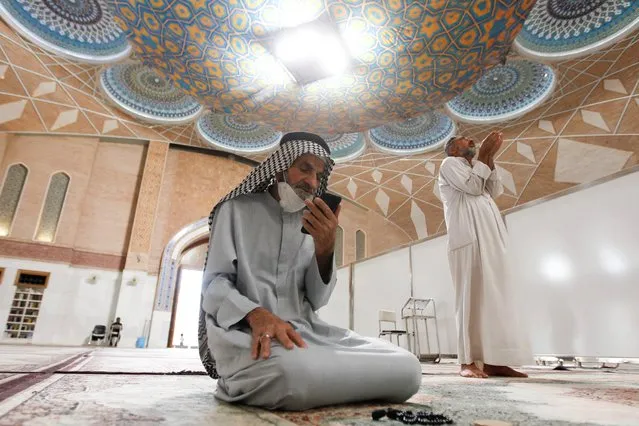 A man using his cellphone prays in a mosque during the holy month of Ramadan in Najaf, Iraq, April 20, 2021. (Photo by Alaa Al-Marjani/Reuters)