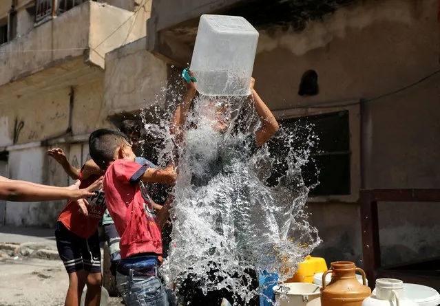 Children play as they fill plastic containers with water in the northeastern city of Hasaka, Syria on August 2, 2023. (Photo by Orhan Qereman/Reuters)