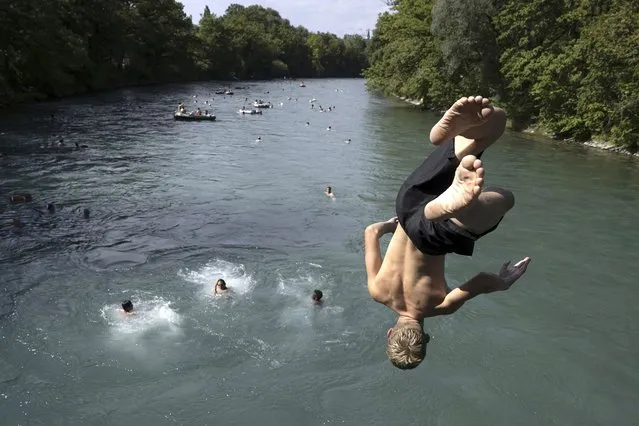 A man jumps from the Schonausteg bridge into the Aare River, during the sunny and warm weather, in Bern, Switzerland, Sunday, August 20, 2023. Many parts of Switzerland have been experiencing a period of extreme heat. (Photo by Anthony Anex/Keystone via AP Photo)
