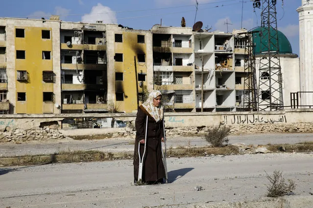 In this Sunday, December 4, 2016 photo, Nisrin Malaji returns to her looted home in the Hanano district of eastern Aleppo, Syria. It's a painful homecoming shared by hundreds of Syrians who are returning to areas devastated by years of war and then retaken from the city's embattled rebels in a recent government offensive. More than 30,000 people have fled Aleppo since the latest government offensive began last month, joining the more than 10 million Syrians – nearly half the population – who have fled their homes since the conflict began. (Photo by Hassan Ammar/AP Photo)