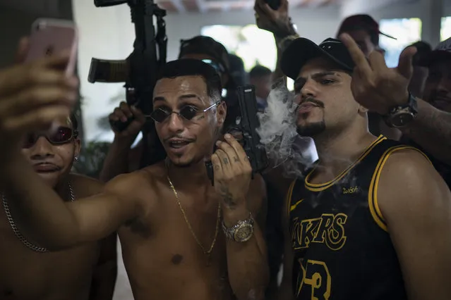 Trap artist Marcos Borges, known as "MbNaVoz," holds an Airsoft gun during a livestream as he records a music video for the song “Se Tem Glock” in the Jardim Catarina community in Sao Gonçalo, Rio de Janeiro state, Brazil, Sunday, April 11, 2021. Most of these rappers aren’t involved with Rio’s so-called factions, or at least not directly. Their millions of YouTube viewers wouldn’t know it from their videos flaunting these Airsoft guns and gold in working-class neighborhoods dominated by drug traffickers. (Photo by Felipe Dana/AP Photo)