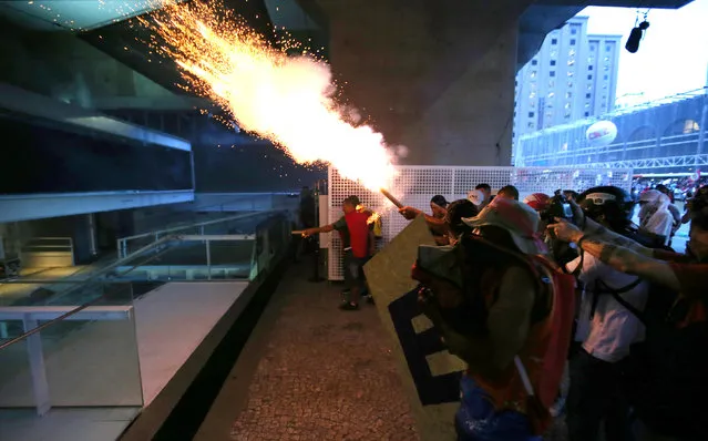 Anti-government demonstrators launch a flare towards the Sao Paulo Industry Federation (FIESP) building during a protest against the constitutional amendment PEC 55, which limits public spending in Sao Paulo, Brazil, December 13, 2016. (Photo by Paulo Whitaker/Reuters)