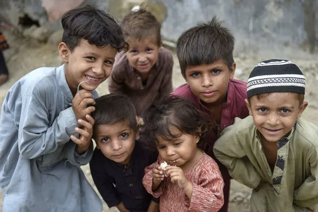 In this photo taken on September 21, 2023, Afghan children pose for photos at an Afghan refugee camp in Karachi. Afghans have poured into Pakistan in their millions during decades of successive wars, many living in aid camps with restricted access to education, healthcare and employment. Around 1.3 million are registered refugees and 880,000 more have legal status to remain in Pakistan, according to the latest United Nations figures. (Photo by Rizwan Tabassum/AFP Photo)