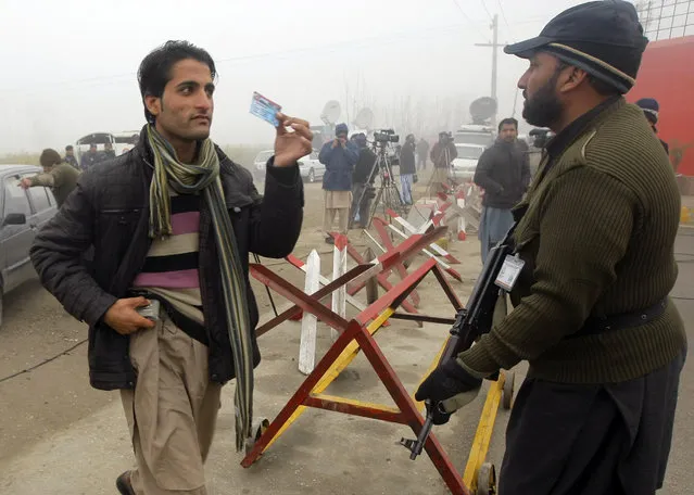 A Pakistani student shows his identity card to a security personnel outside the Bacha Khan University in Charsadda, Pakistan, Monday, January 25, 2016. Officials say a northwestern Pakistani university where Islamic militants gunned down 21 students and teachers last week has reopened for classes amid tight security. (Photo by Mohammad Sajjad/AP Photo)
