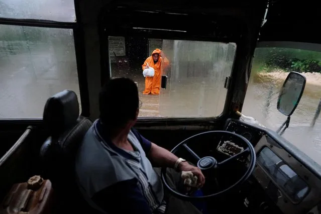 Joel Garcia, 53, drives a school bus to evacuate a woman from her home as Storm Idalia makes landfall in Cuba, Guanimar, Cuba on August 28, 2023. (Photo by Alexandre Meneghini/Reuters)