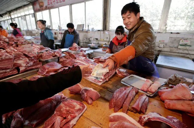 A butcher selling pork returns change to a customer at a market in Beijing, China March 25, 2016. (Photo by Jason Lee/Reuters)