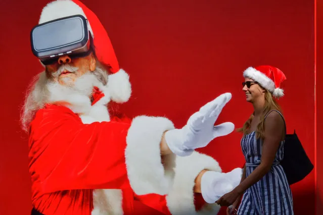 A woman walks past a giant Santa Claus poster at Jumeirah Beach Residence in Dubai on December 25, 2018. (Photo by Giuseppe Cacace/AFP Photo)