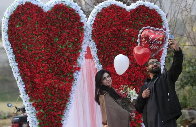 A couple takes a selfie as they stand next to a heart-shaped paper flower decoration at flower market on Valentine's Day in Islamabad, Pakistan, February 14, 2016. (Photo by Faisal Mahmood/Reuters)