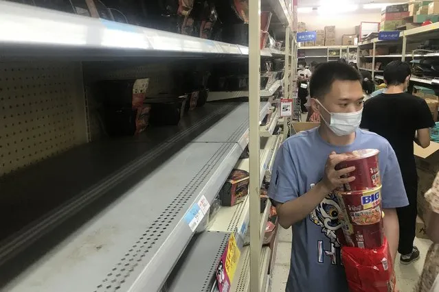 Shelves are empty as residents rush to stock up on necessities at a supermarket after authorities lockdown near residential blocks to prevent the spread of the COVID-19 in Wuhan city in central China's Hubei province Monday, August 2, 2021. Chinese authorities announced Tuesday the mass testing of Wuhan as an unusually wide series of COVID-19 outbreaks reached the city where the disease was first detected in late 2019. (Photo by Chinatopix via AP Photo)