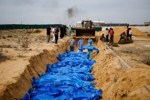 The bodies of Palestinians killed in Israeli strikes and fire are buried in a mass grave, after they were transported from Al Shifa hospital in Gaza City for burial, in Khan Younis in the southern Gaza Strip on November 22, 2023. (Photo by Mohammed Salem/Reuters)