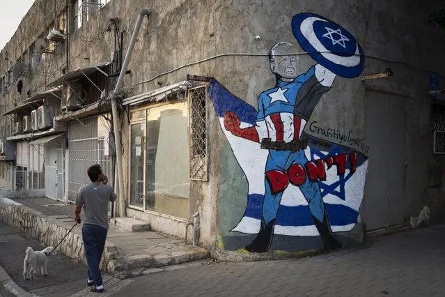 A man walks past a newly painted graffiti of Joe Biden depicts the U.S. president as a superhero defending Israel, Tel Aviv, Israel, Monday, October 30, 2023. Biden's popularity in Israel has soared thanks to his strong support for Israel in its war against Hamas militants. (Photo by Oded Balilty/AP Photo)