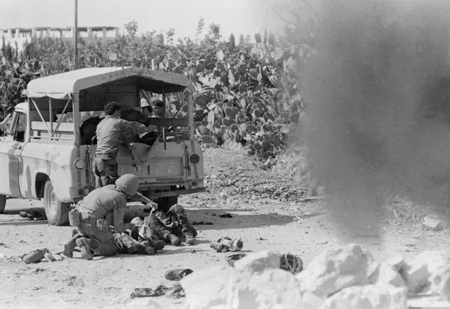 An Israeli soldier gives first aid treatment to men injured when a car full of newsmen was blown up by a booby-trapped stone barricade left by retreating Egyptians on the road to Gaza when it was taken by Israeli troops, June 6, 1967.  (Photo by Kurt Strumpf/AP Photo)